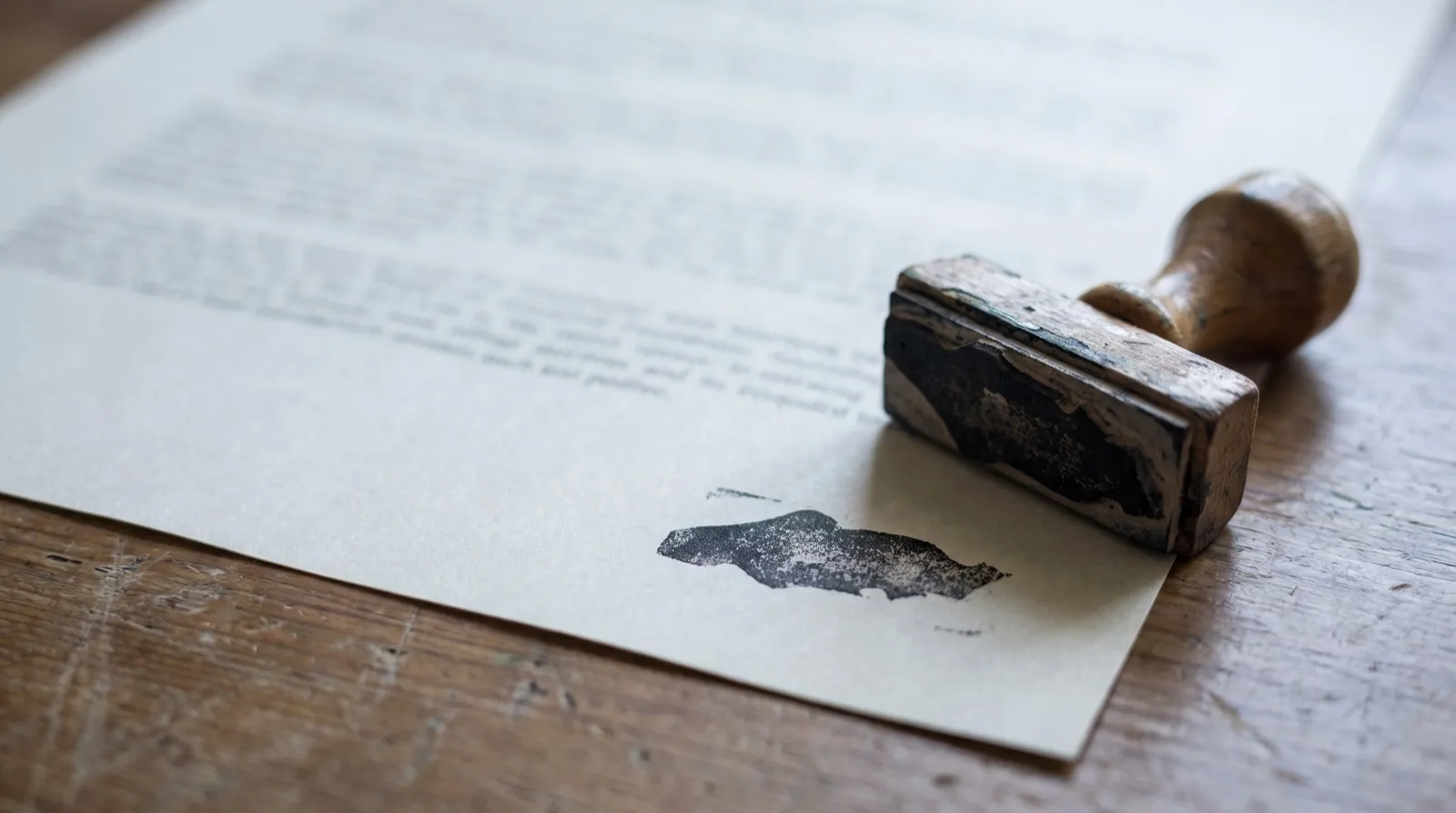 Documento impreso sobre un escritorio con la huella fresca de un sello de caucho en la esquina.
