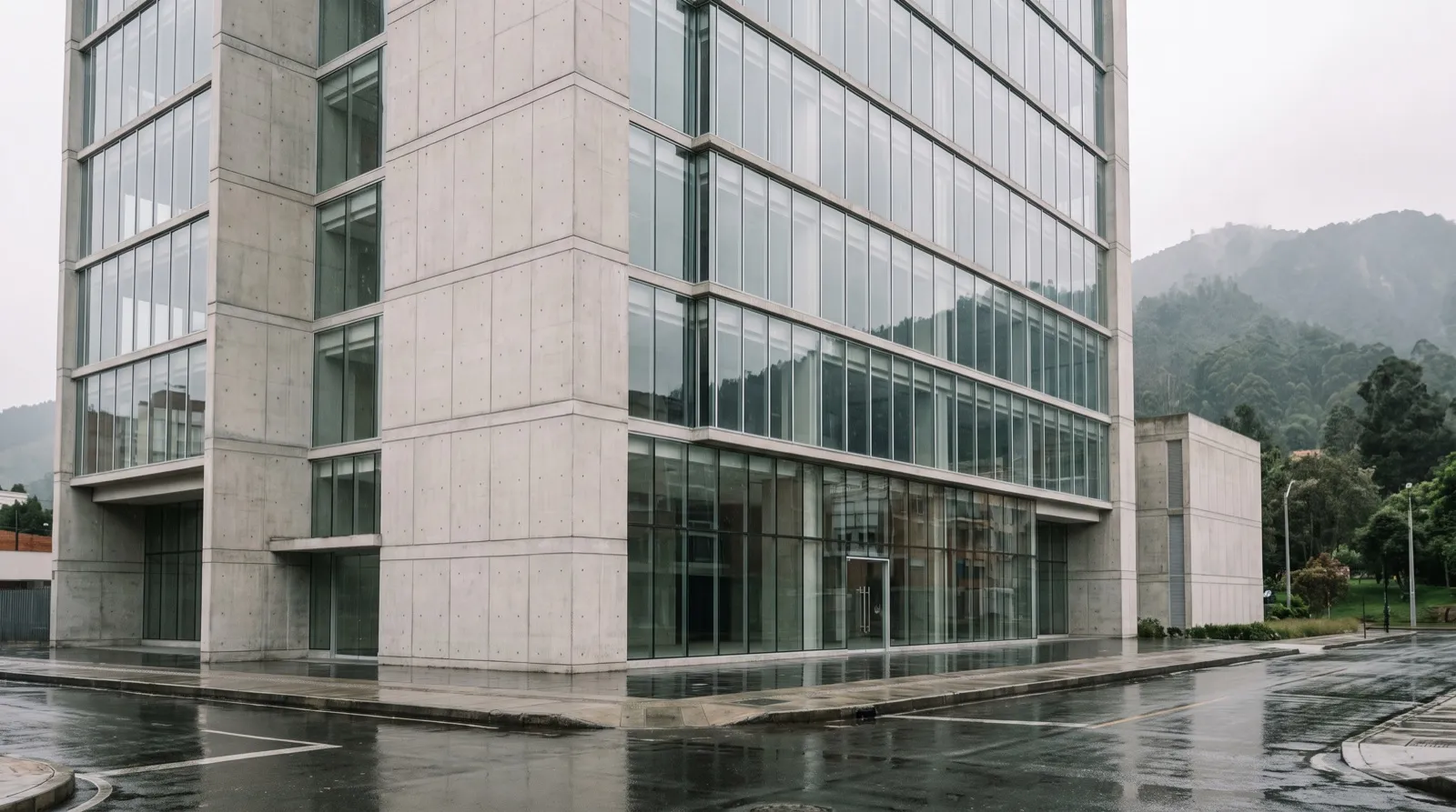 Fachada de vidrio y concreto de un edificio de oficinas moderno en Bogotá, con los cerros al fondo.